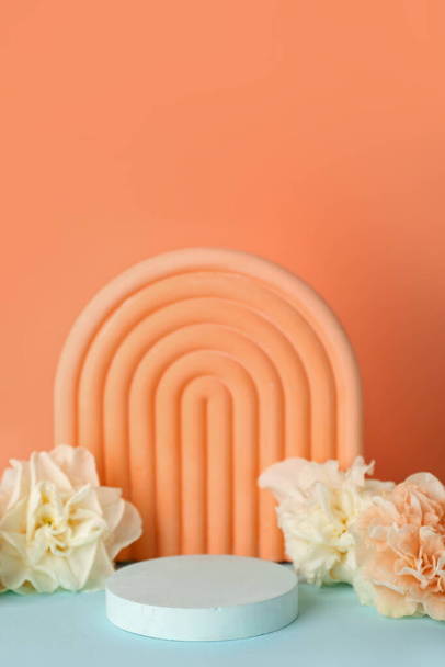Dekoratív gipsz dobogók virágokkal a türkiz asztal narancssárga háttér - Fotó, kép