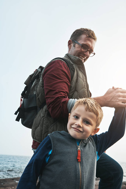 Papá no me suelta la mano. un alegre padre e hijo tomados de la mano mientras caminan al lado del océano durante el día - Foto, imagen