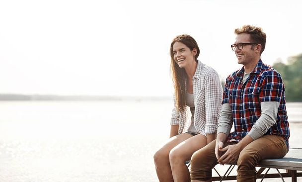 Get away form the city and get back to nature. a happy young couple sitting on a pier - Photo, Image
