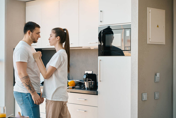 Husband and wife emotionally sort things out in the kitchen, guys in home clothes - Фото, зображення