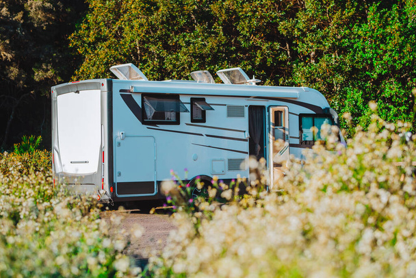 Modern motorhome camper van camping car parked in the nature in free parking and off grid vanlife lifestyle concept. Travel and summer holiday renting vehicle vacation. Green nature park background - 写真・画像