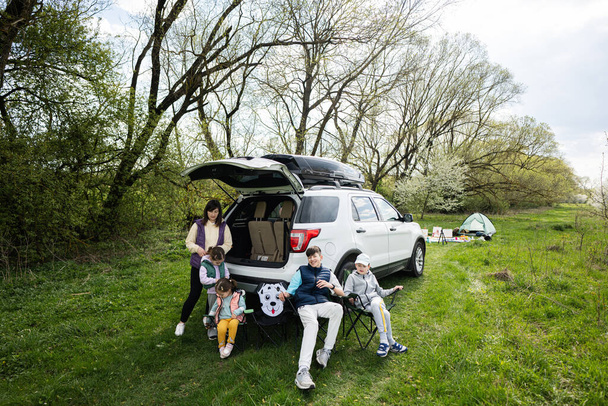 Mother with kids sit on chair against car on picnic. - Foto, Bild