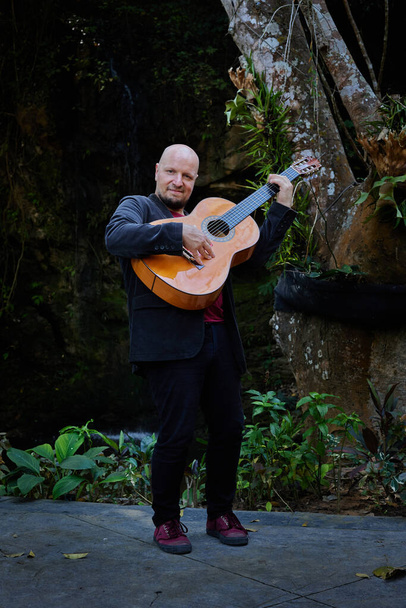 Guitarrista acústico que ofrece una actuación cautivadora en la naturaleza. Foto de alta calidad - Foto, Imagen