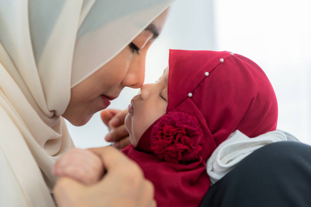 Muszlim család, ázsiai anya, aki két hónapos újszülött lányának orrát fogja és csókolgatja, aki alszik, szeretettel és boldogsággal. a kapcsolat muszlim család és az iszlám gyermekek koncepciója. - Fotó, kép