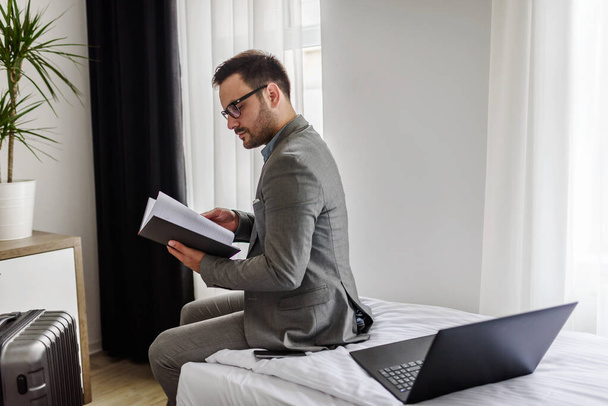 Traveling for work. Elegant businessman sitting in his hotel room working - Photo, Image