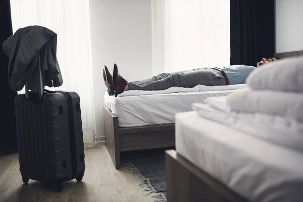 mężczyzna leżący na łóżku w pokoju hotelowym - Zdjęcie, obraz