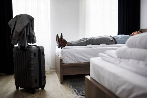 muž ležící na posteli v hotelovém pokoji - Fotografie, Obrázek