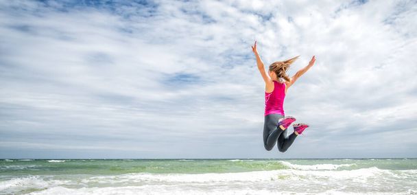 Happy beautiful young girl jumping at the sea - Foto, Bild