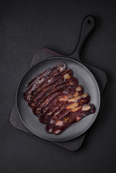 Delicious smoked or cured mahan horse meat sausage with spices and herbs on a dark concrete background - Foto, Imagem