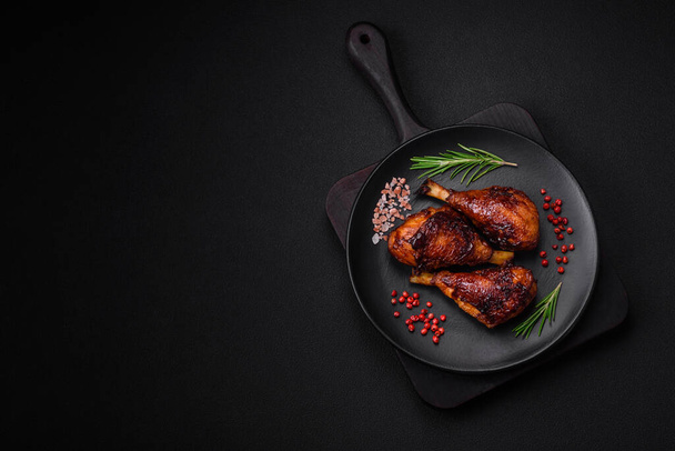Delicious grilled chicken legs with spices and herbs in teriyaki sauce on a dark concrete background - Fotografie, Obrázek