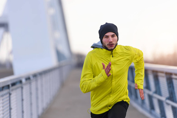 Attractive fit man running fast along big modern bridge. Exercising, Jogging, Sport, Winter. Male athlete running. - Fotoğraf, Görsel