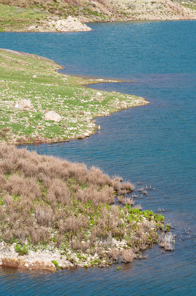 Zelené skalnaté kopce a modrá voda přehrady Mavrokolympos v Peyii, Kypr - Fotografie, Obrázek