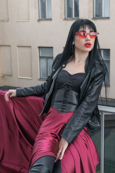 Mulher com cabelo comprido, figura perfeita, sexy. ela está em um cetim, saia vermelha longa, jaquetas de couro. Posando na cidade - Foto, Imagem