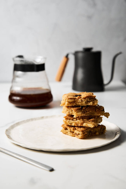 blondie cookies squares on white plate. Composition of sweet breakfast with coffee and blondie cookies. High quality photo - Foto, Imagem