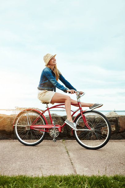 No te preocupes por mí. una joven alegre montando su bicicleta por una calle mientras realiza trucos fuera durante el día - Foto, imagen