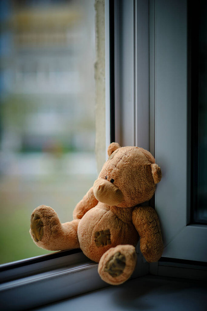 Niedźwiedź dzieci miękka zabawka siedzi krawędź otwarte okno.Concept wypadków z dziećmi - Zdjęcie, obraz
