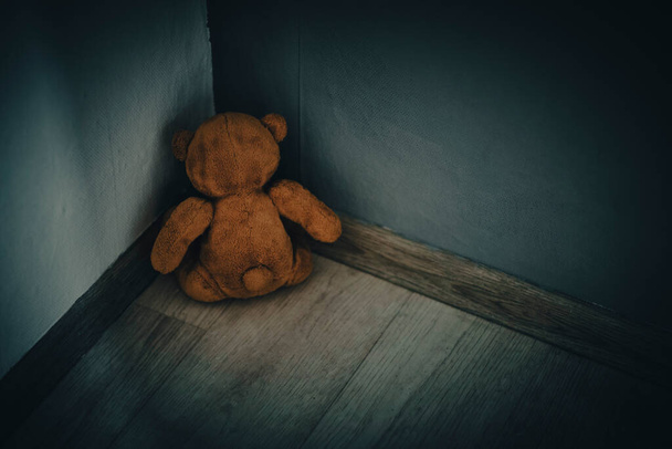 Teddy bear soft toy sitting corner room.Concept of domestic violence against children - Zdjęcie, obraz