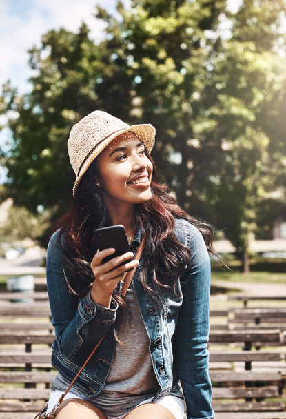 Ничего кроме спокойного и беззаботного дня. привлекательная молодая женщина, пользующаяся мобильным телефоном в парке - Фото, изображение