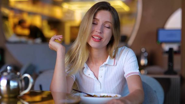 Beautiful joyful young female sitting in restaurant and talking to camera. Close up of happy pretty woman on a date in bar speaking and looking at camera in positive mood and smiling. Cafe concept - Foto, immagini