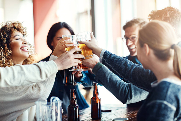 Es lebe die gute Zeit. eine Gruppe glücklicher Freunde prostet mit Bier an einer Bar zu - Foto, Bild