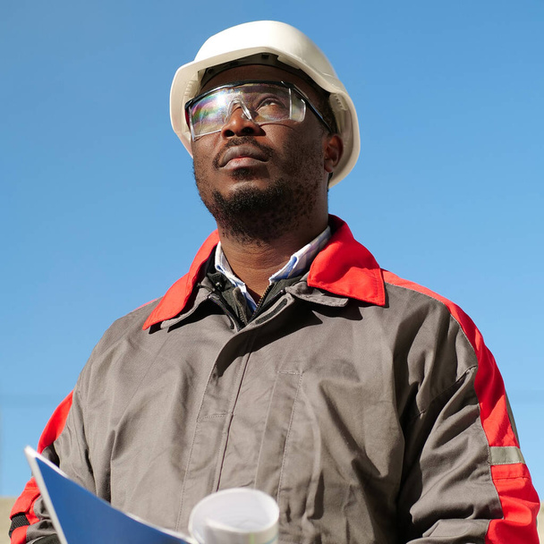 Африканський робітник стоїть на будівельному майданчику з робочими паперами. - Фото, зображення