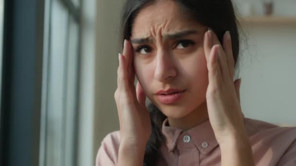 Unavená nemocná žena arabský indický dívka v blízkosti okna doma trpí bolestí hlavy dotek bolestivé hlavy migréna bolest nezdravý nemocný žena myslet obtížné myšlenky smutek zdraví porucha stres únava covid - Záběry, video