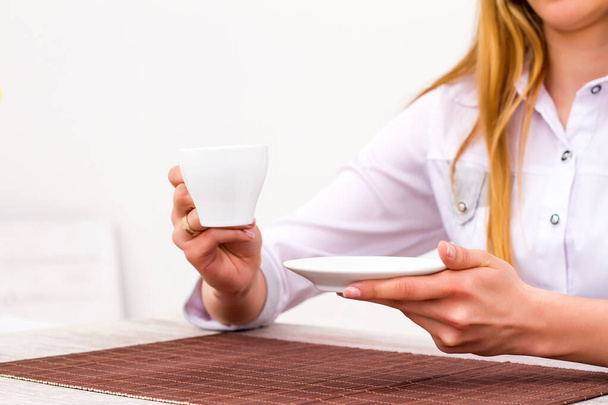 Πρωινός καφές. Μια γυναίκα κρατάει ένα άσπρο φλιτζάνι. - Φωτογραφία, εικόνα