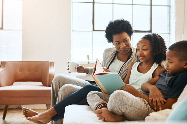 Дети больше всего выигрывают от чтения. младшие брат и сестра читают книгу, в то время как их мать смотрит дома - Фото, изображение
