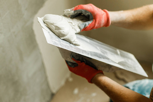 Alçı taşı ve spatulayla duvarları sıvayan bir işçi. Ev ve ev yenileme konsepti. # Yaklaş sıva ve becerikli ellerin malayla # - Fotoğraf, Görsel