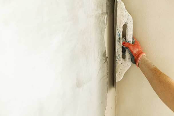 Handyman gips muren met gips en troffel. Bouw van huis-en woningrenovatie concept. Sluiten van de handen van de werknemer met spatel en stucwerk - Foto, afbeelding