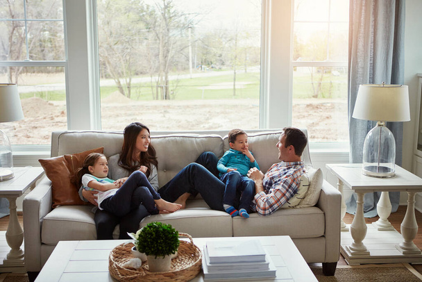 Home is where love lives. a happy young family of four relaxing together on the sofa at home - 写真・画像