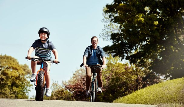 Давайте подивимося, хто першим дістанеться до фінішу. молодий хлопчик і його батько катаються разом на велосипедах
 - Фото, зображення