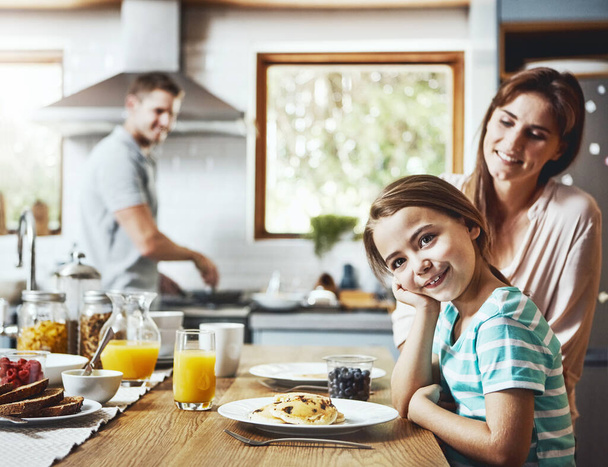 El desayuno es el momento más delicioso del día. Retrato de una niña desayunando con sus padres en casa - Foto, imagen