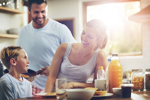 Su cara se ilumina cuando está con su familia. un niño desayunando con sus padres - Foto, imagen
