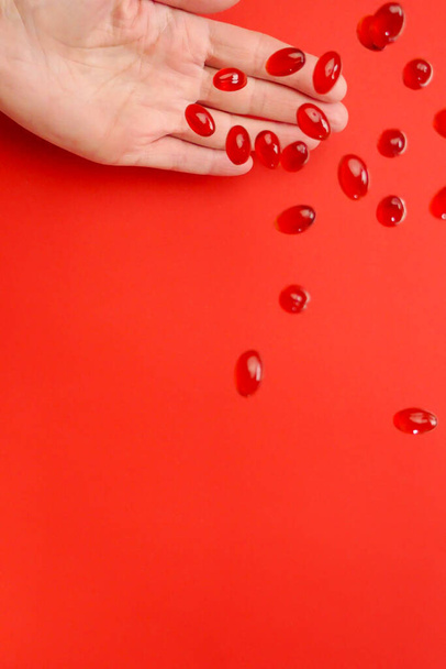 Krill oil capsules .omega fatty acids.Flying gelatin red krill oil capsules in a hand on a red background. Natural supplements  - Photo, Image