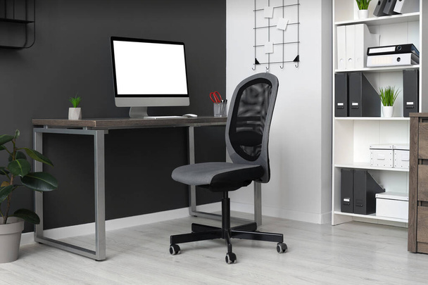 Stylish office interior with comfortable chair, desk and computer - Foto, Imagen