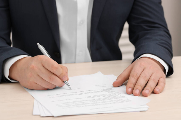 Man signing document at wooden table, closeup - Foto, imagen