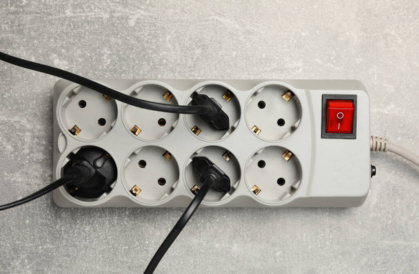 Power strip with extension cord on light grey table, top view. Electrician's equipment - Φωτογραφία, εικόνα