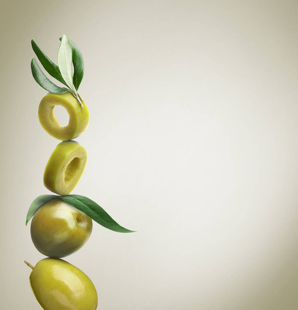 Cut and whole green olives with leaves on dusty beige background, space for text - Fotoğraf, Görsel