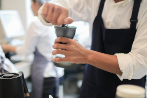 バリスタコーヒードリッパーと漏斗に挽いたコーヒーとフィルターを注ぐ。醸造プロセスでレストランやカップで働く。コーヒーショップのコンセプト. - 写真・画像