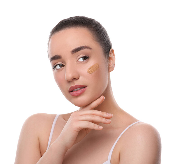 Woman with swatch of foundation on face against white background - Fotó, kép