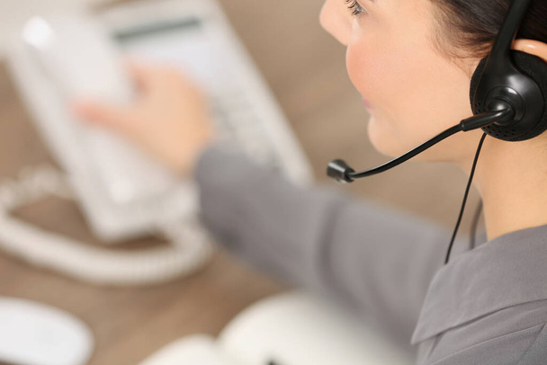 Hotline operator with headset and stationary phone working in office, closeup. Space for text - Fotó, kép