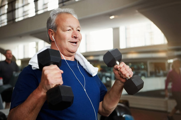 Anche la forma fisica può essere divertente. un uomo anziano che lavora con i pesi in palestra - Foto, immagini
