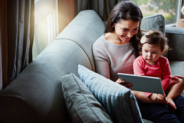 Dijital çağdan öğreniyorum. Bir anne ve sevimli küçük kızı evde dijital tablet kullanıyorlar. - Fotoğraf, Görsel