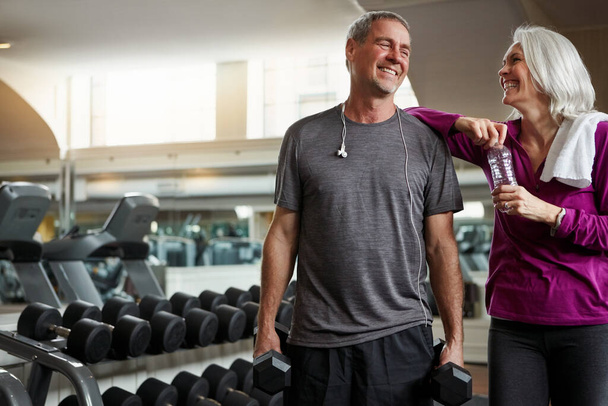 Wir gegenseitig motivieren uns für Fitness. ein älteres Ehepaar lacht und macht eine Pause vom Training im Fitnessstudio - Foto, Bild