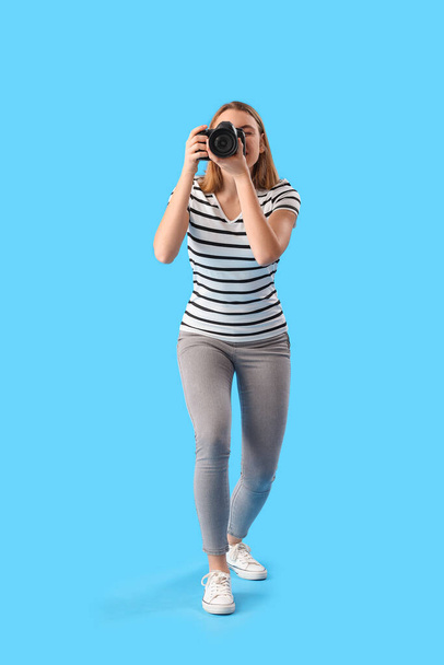 Fotógrafo femenino con cámara profesional sobre fondo azul - Foto, imagen