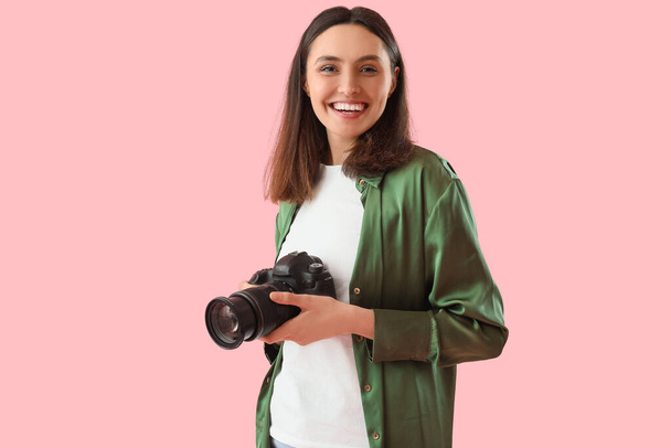 Fotógrafo femenino con cámara profesional sobre fondo rosa - Foto, Imagen