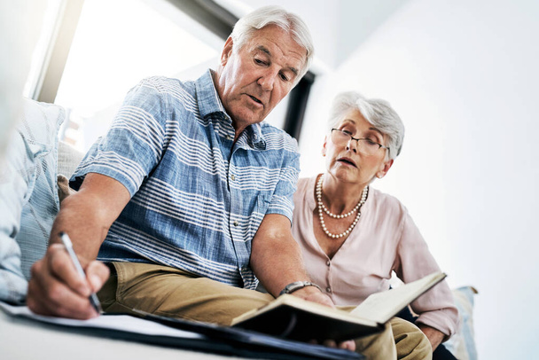 Surveiller leurs finances de près. un couple de personnes âgées qui fouillent leur paperasse ensemble à la maison - Photo, image