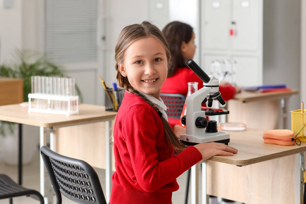 Little girl with microscope having Chemistry lesson in science classroom - Fotó, kép