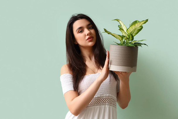 緑の背景に観葉植物を持つ若い女性 - 写真・画像